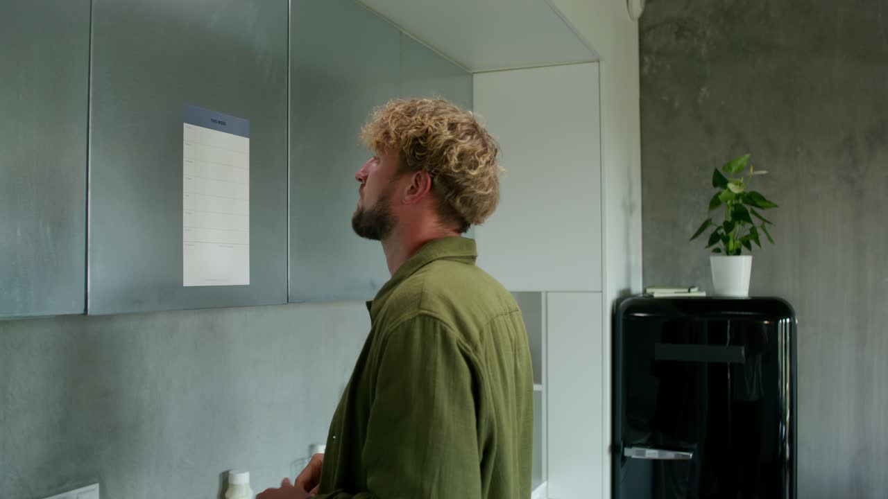 Man writing on a wall calendar in a modern kitchen