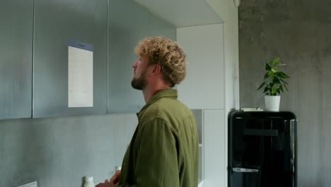 man writing on a wall calendar in a modern kitchen