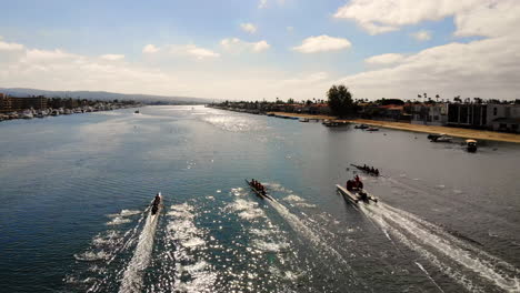 Rowing-Crew-regatta-race-in-Newport-Harbor,-California-with-three-8-man-boats-approaching-finish-line-on-sunny-morning