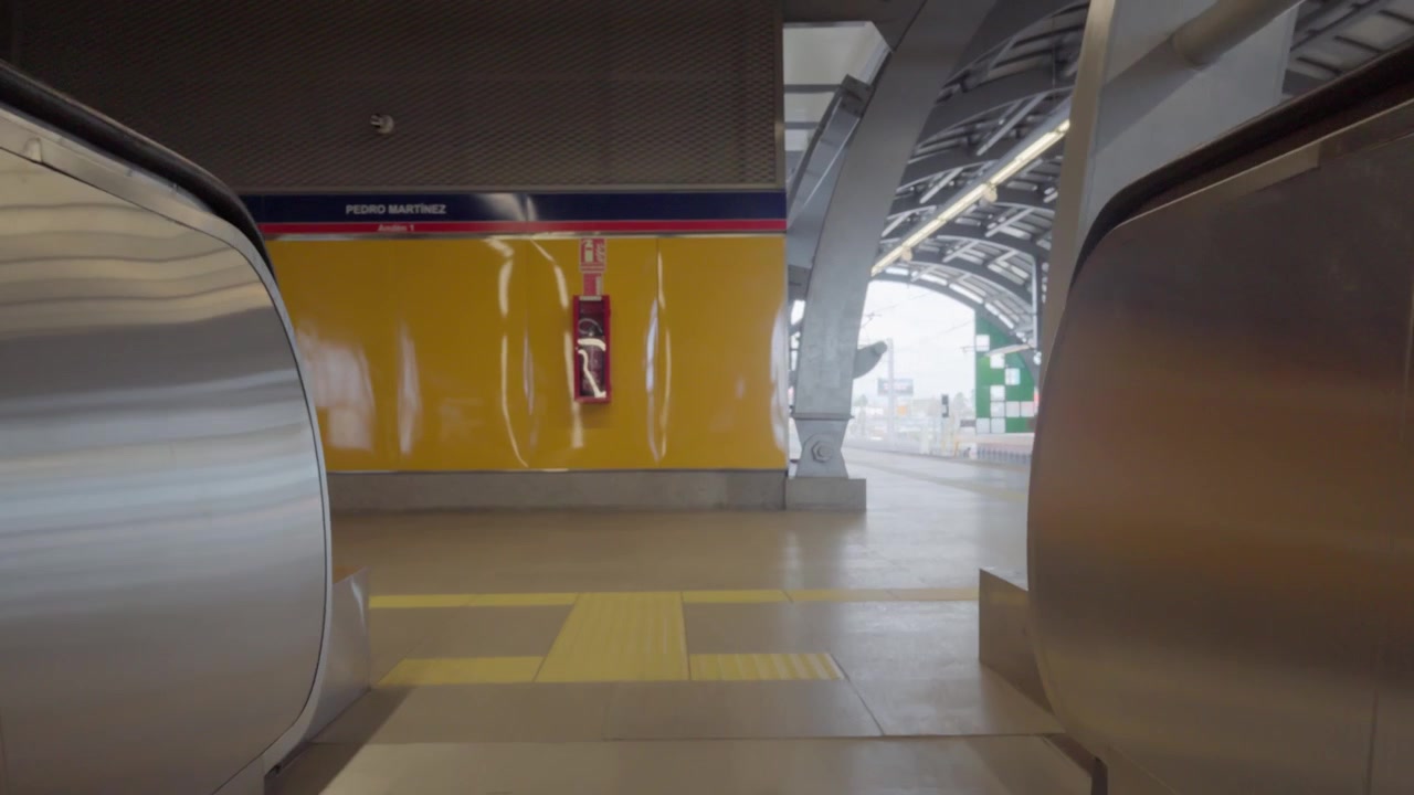 Una ripresa in prima persona che sale una scala mobile e arriva al livello della banchina di una moderna stazione della metropolitana.
