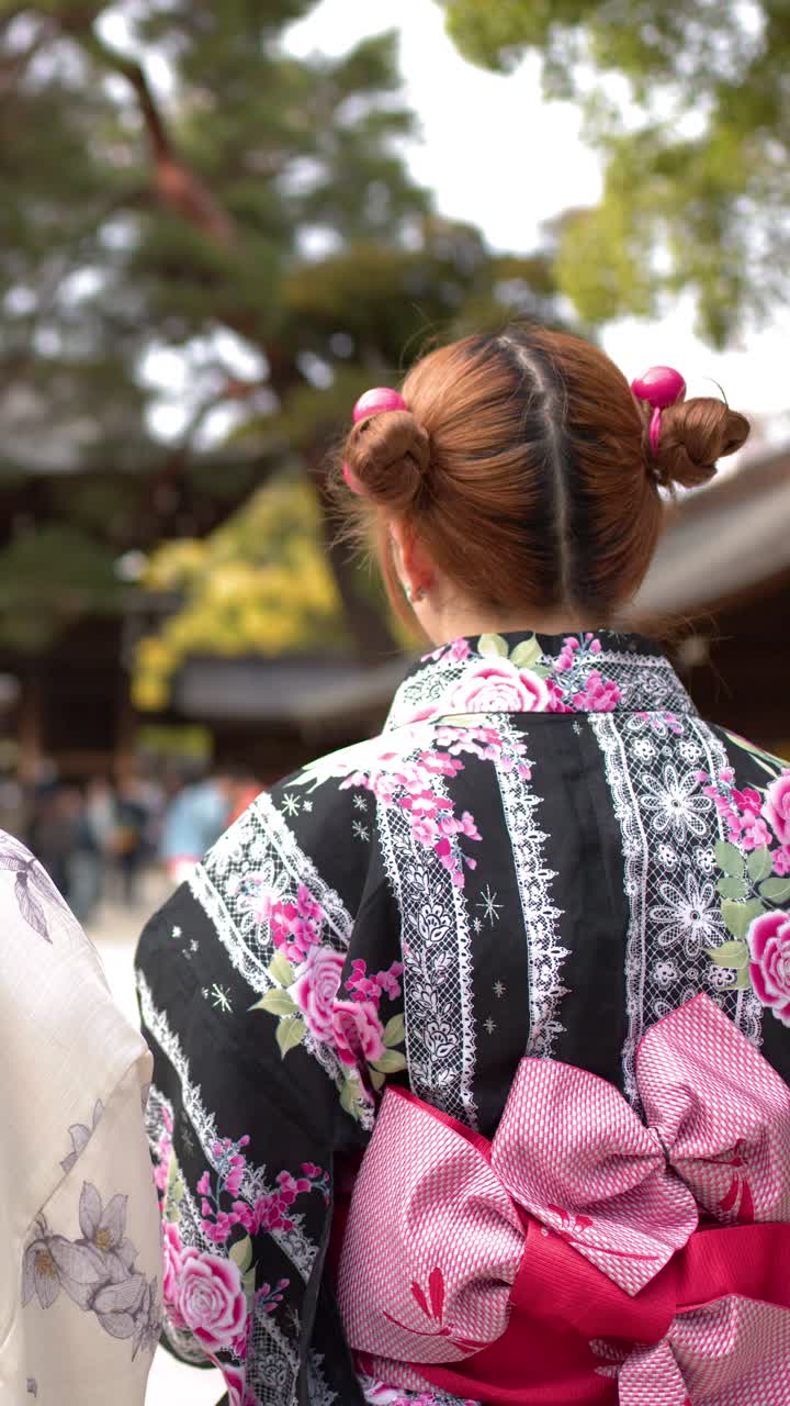 東京の歴史ある日本の神社で、花柄の着物を着た女性が丁寧に頭を下げている。