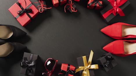 Red-and-black-shoes,-gift-bags-and-gift-boxes-on-black-background-with-copy-space