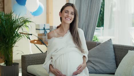 portrait of smiling pregnant woman with blue decorations outdoors.