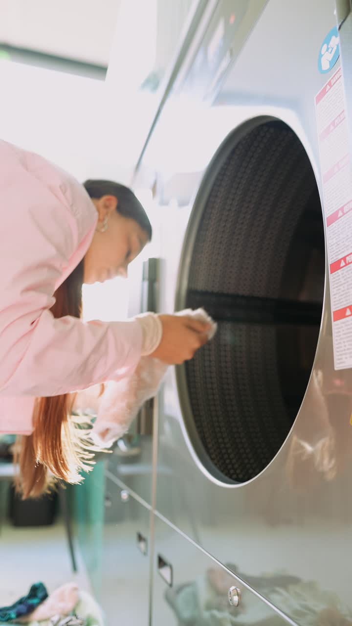 Woman doing laundry in a self-service laundry room