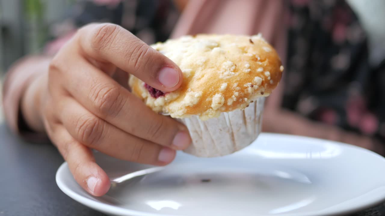 la mano sosteniendo un muffin de arándanos