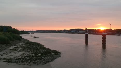 River-Schelde-and-golden-color-sunset-over-small-town,-aerial-view