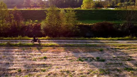 Moped-In-Der-Goldenen-Stunde-Auf-Einem-Schotterweg,-Filmischer-Drohnenschuss