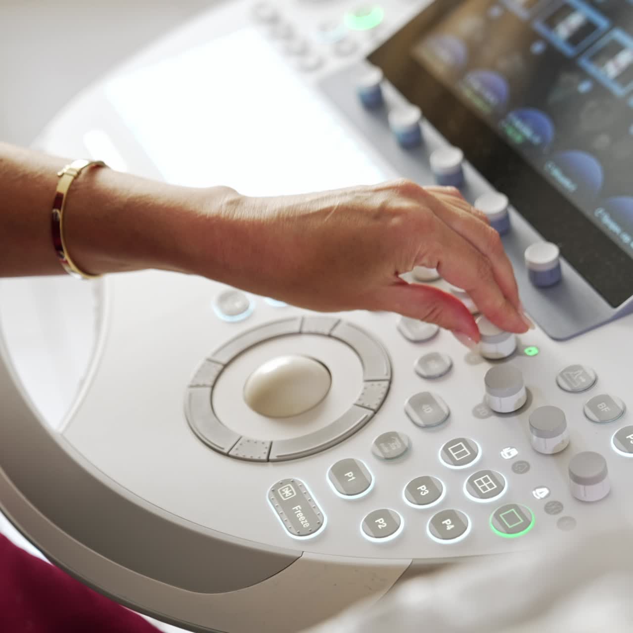 Female doctor's hand pressing the buttons on the sensor screen. Obstetrician operating the ultrasound equipment at modern clinics. Top view