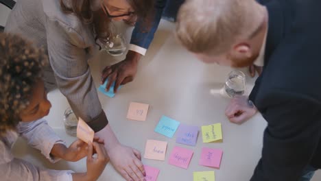 business people writing reminders on colorful stickers at table in office. work planning concept