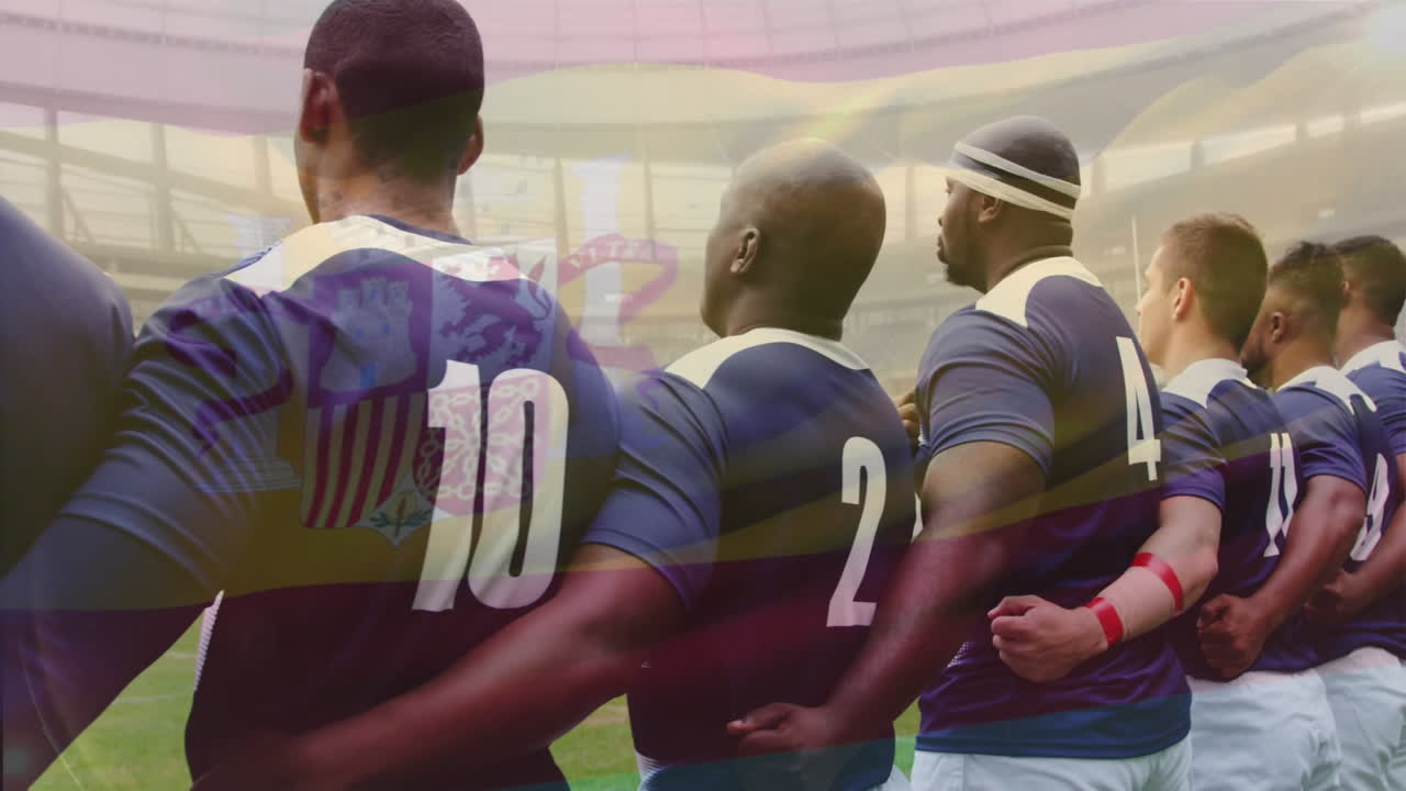 Standing together, rugby players linking arms wearing numbered jerseys on field