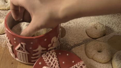 mani della donna che mettono i biscotti fatti a mano in un barattolo di biscotti