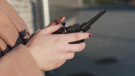 primer plano de la mano femenina volando un dron en medio del día