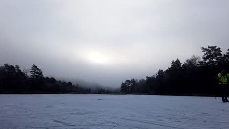 timelapse of ice skaters skating on frozen lake with dramatic clouds, winter landscape