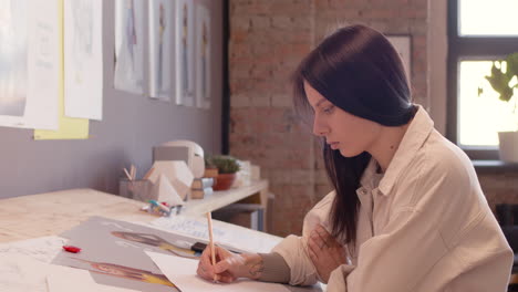 diseñadora gráfica concentrada dibujando mientras se sienta en el escritorio de dibujo en un estudio de animación