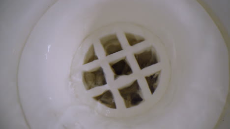 macro close up of a bathtub plug hole as water gently turned on to run down the hole