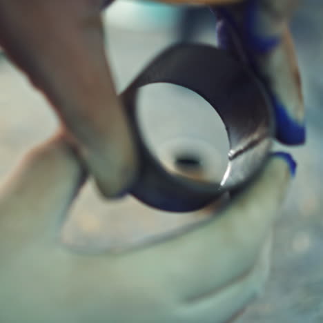 a man holds a ball bearing in his hand and colors it inside using a brush on the manufacturing. close-up. blurred background.