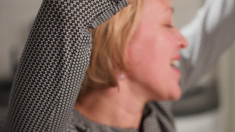 elegant fair skinned grandmother raises hands high in excitement while passionately singing song in modern kitchen, expressing pure joy and emotion through body language and graceful hand movements
