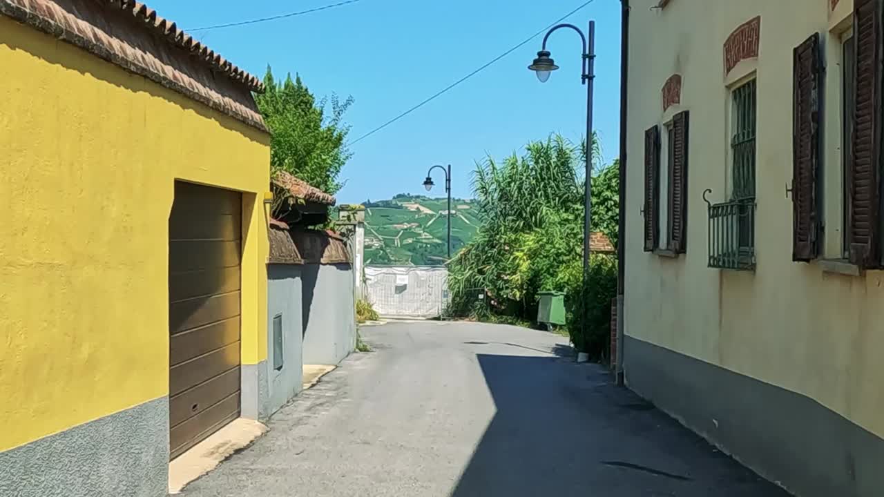 callejón soleado con edificios amarillos y vegetación