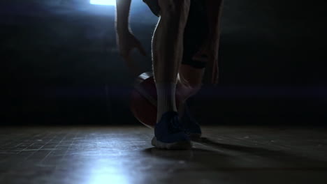 Dribbling-basketball-player-close-up-in-dark-room-in-smoke-close-up-in-slow-motion