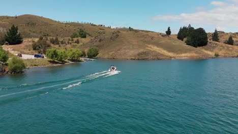 Aerial---Boat-on-Lake-Dunstan,-Central-Otago,-New-Zealand-with-mountains-and-clouds-in-background