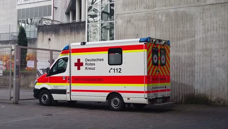 stationary profile view of german ambulance vehicle on standby at station entrance