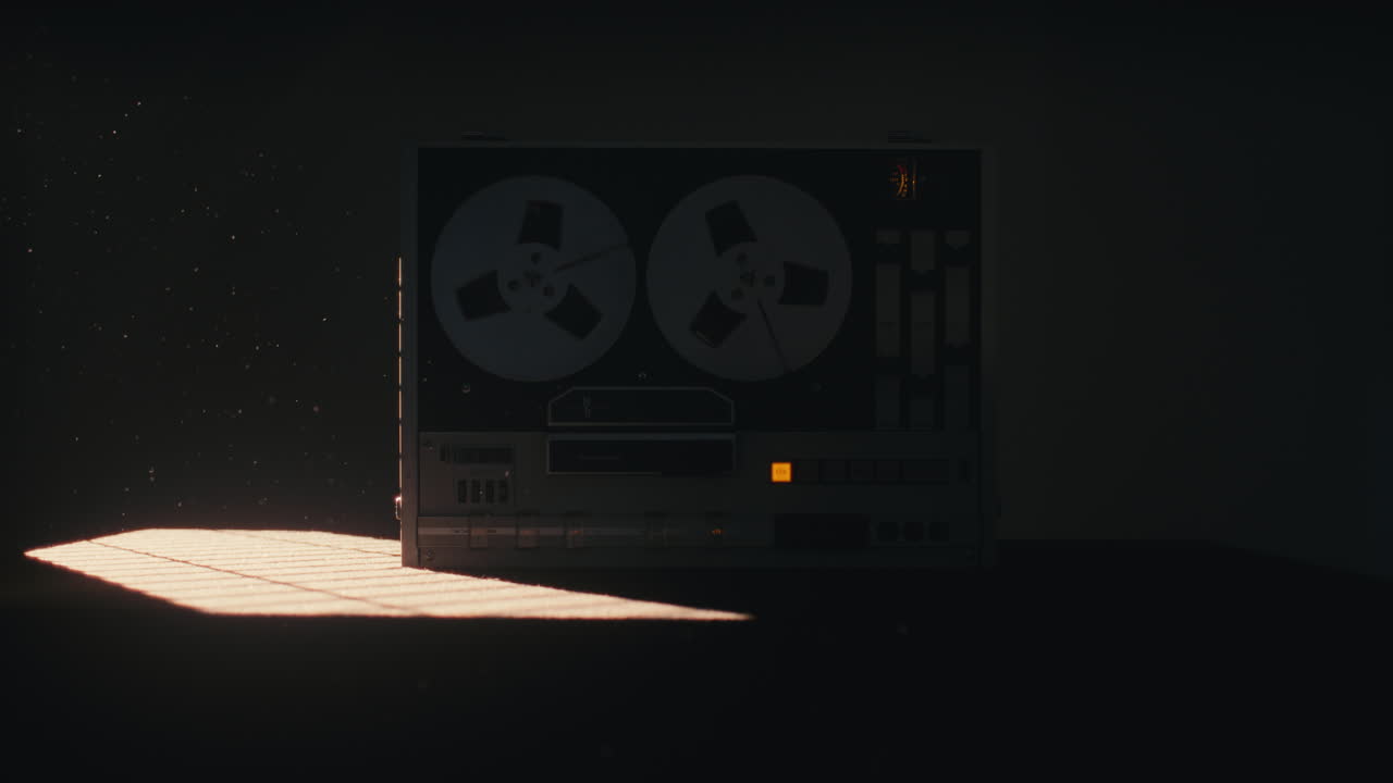 A vintage tape recorder spinning spools in a red blinking light