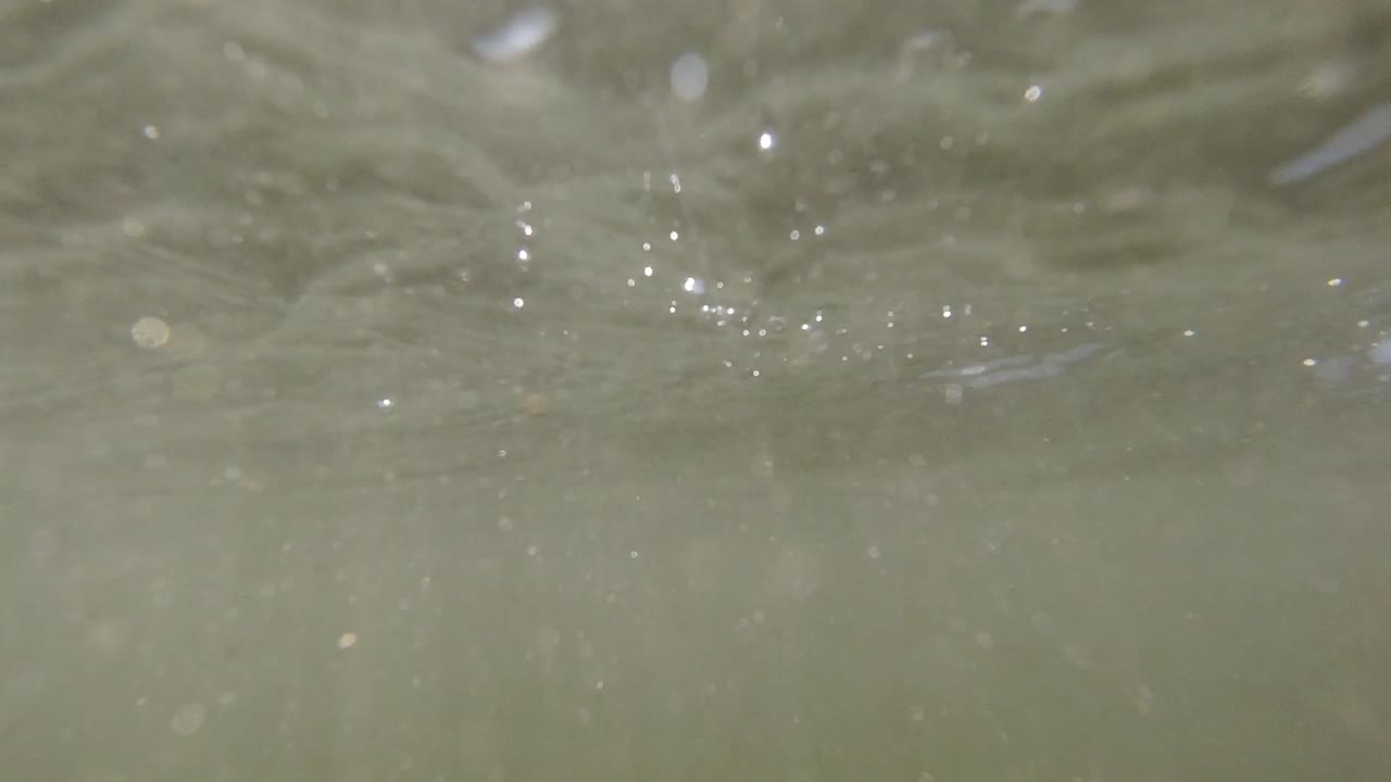 바다 표면에서 떠다니며 파도가 천천히 카메라 렌즈 위를 굴러가면서 태양 플레어 - 초 느린 동작 영상