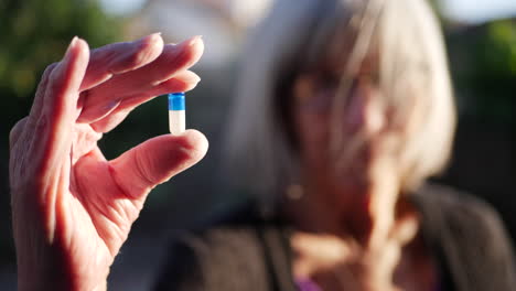 una anciana sosteniendo una píldora de medicamentos recetados para mejorar su salud y curar enfermedades