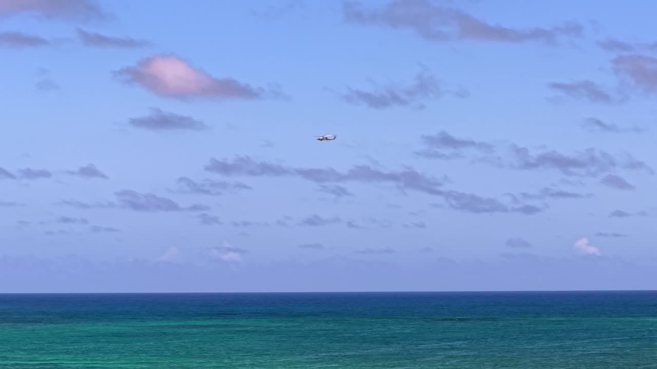 Helicopter flies over the turquoise ocean in Hawaii on a sunny day
