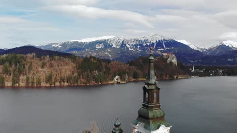 bled lake. drone fly over a christian old church with amazing mountain landscape snow peaks and little village