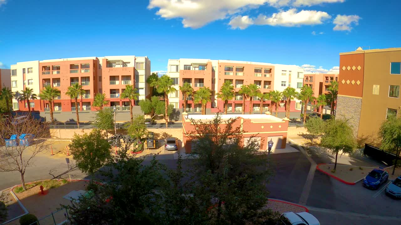 pan de video de izquierda a derecha, avenida del parque coindo edificios con palmeras y coches