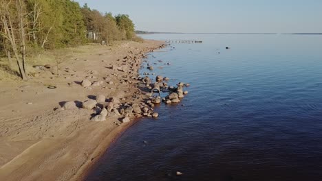 rocky beach shore with many boulders and blue sea nordic nature, naked trees