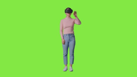 toma completa de una mujer con auriculares de realidad virtual e interactuando contra el fondo del estudio de pantalla verde 1