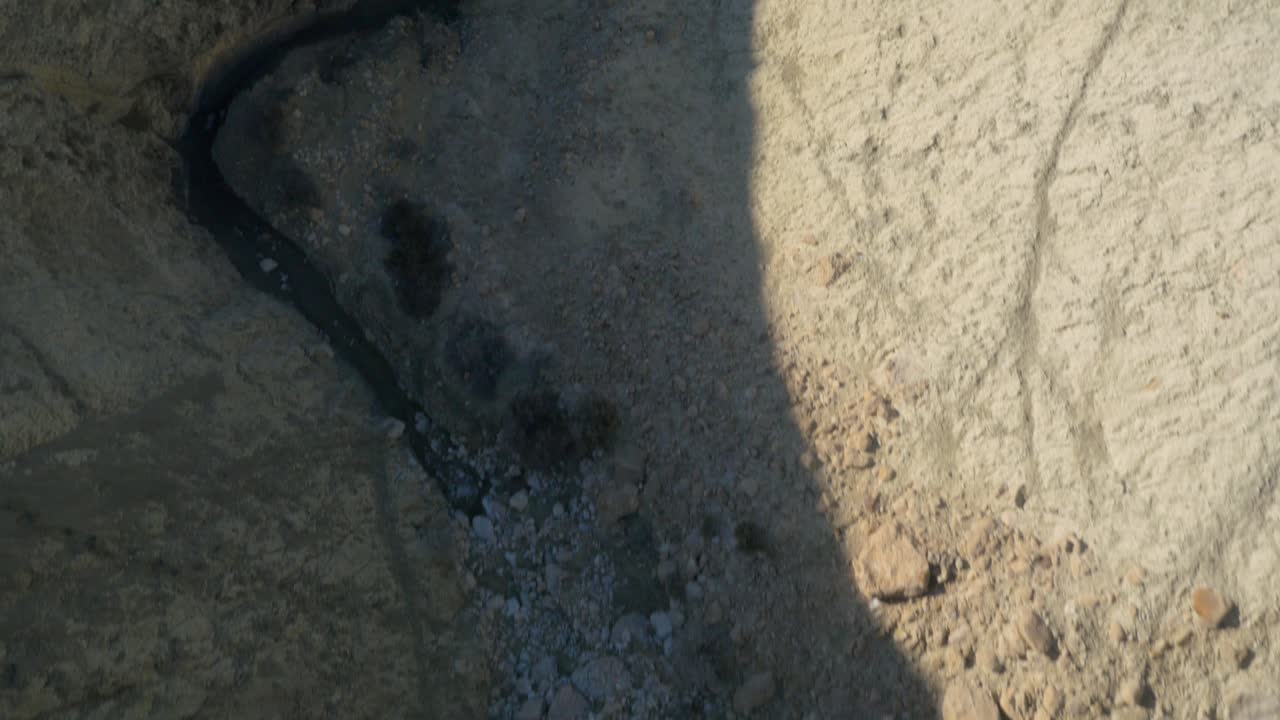 cañón árido y rocoso aéreo de arriba hacia abajo con un pequeño arroyo