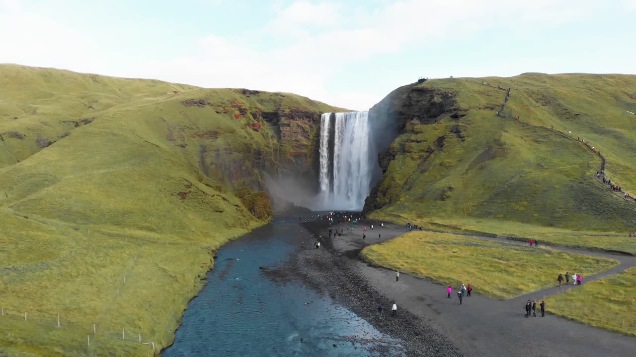 multitud de turistas en la orilla del río visitando la cascada de skogafoss en islandia