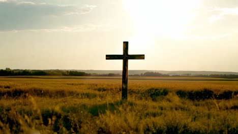 wooden cross in a field at sunset