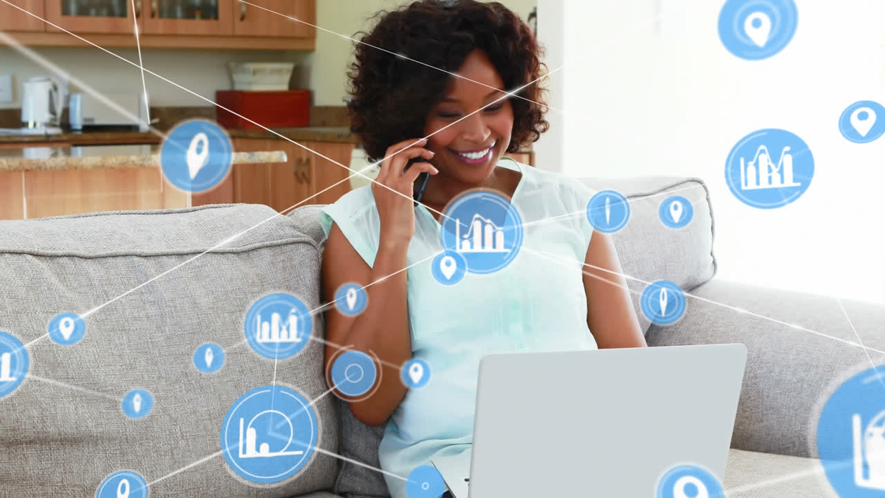 Animation of connected icons over african american woman talking on cellphone and working on laptop