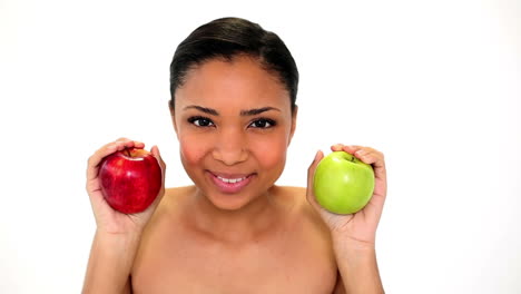 hermosa mujer joven sosteniendo dos manzanas oliéndolas