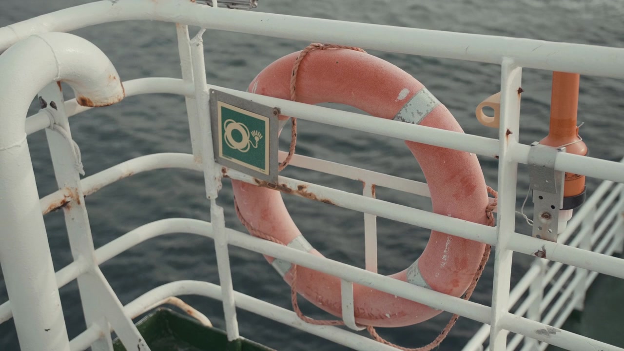 Salvagente arancione appeso alla ringhiera di una nave in mare
