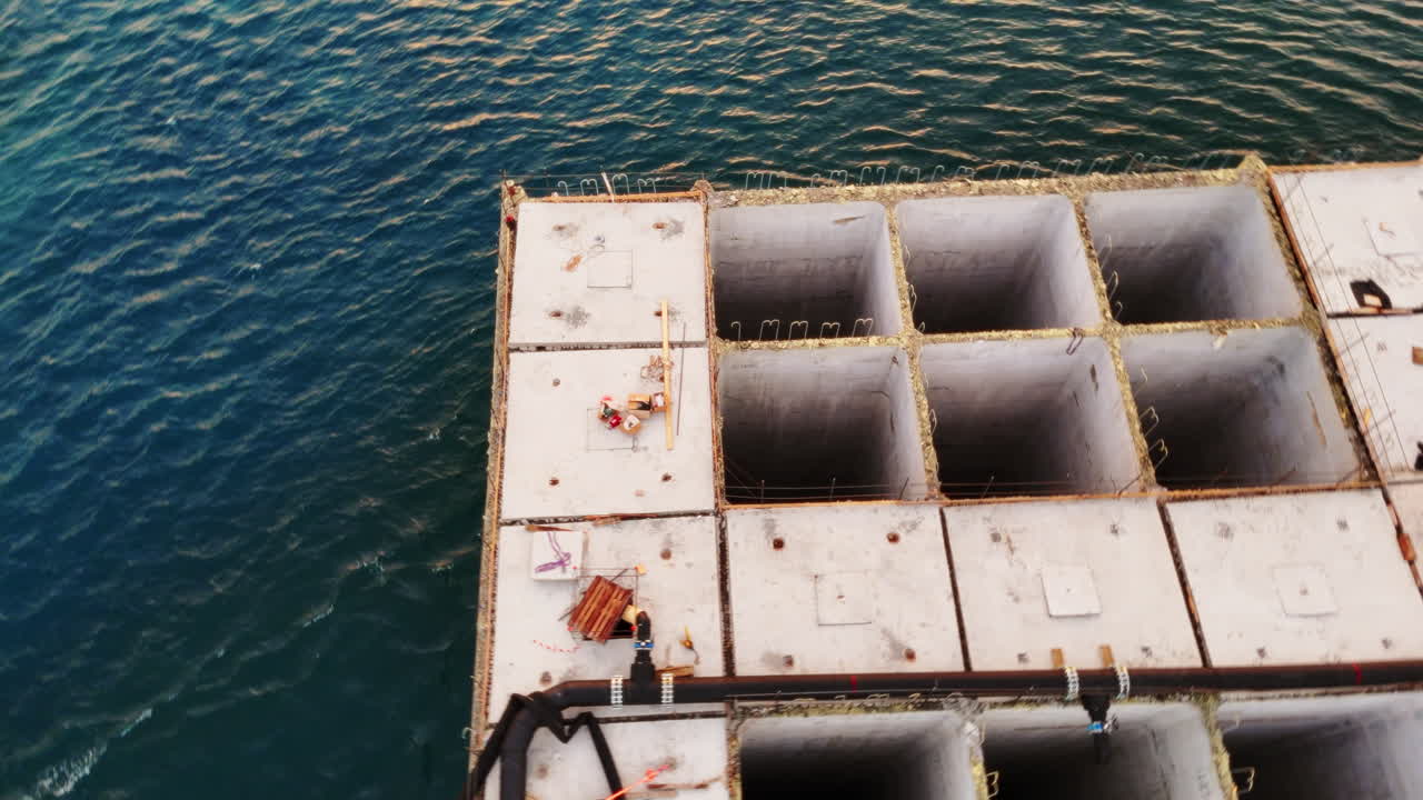 Concrete building base structure in the sea at sunset. Aerial