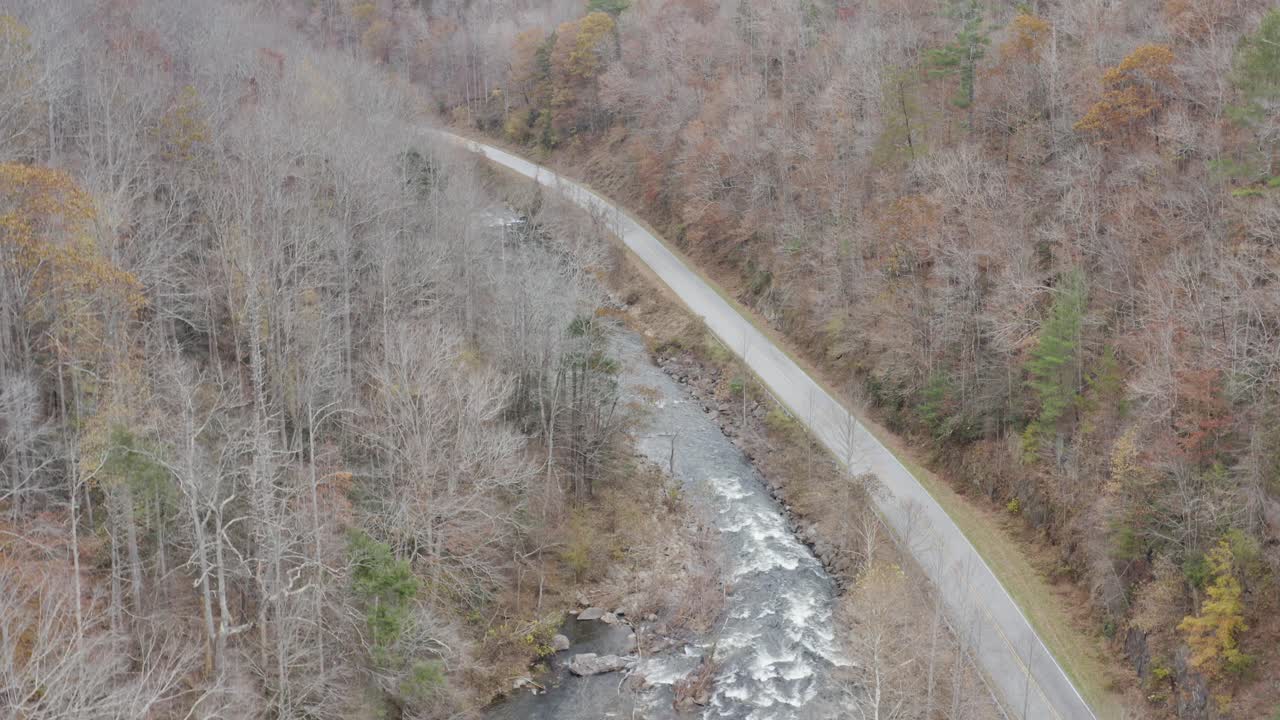 Droneoptagelse af flod og vej set nedstrøms med stigende højde sent efterår i det vestlige North Carolina