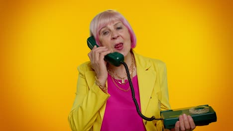 Crazy-elderly-granny-old-woman-talking-on-wired-vintage-telephone-of-80s,-fooling-making-silly-faces