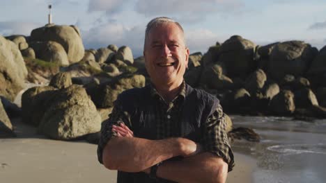 Senior-man-smiling-at-camera-at-the-beach