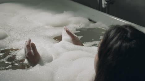 unknown lady taking bath in luxury hotel. back view woman lying in home bathtub