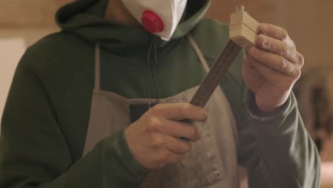 hardworking professional carpenter in mask and glasses holding a ruler