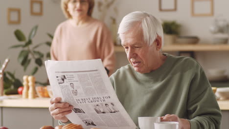 senior man reading newspaper and having coffee in morning