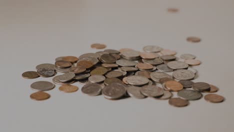 monedas cayendo sobre un montón de cambio en cámara lenta