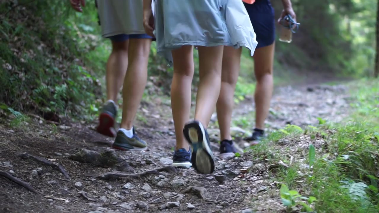Una famiglia che fa la sua passeggiata ed esercizio mattutino su un sentiero stretto che sale verso la foresta - Primo piano.