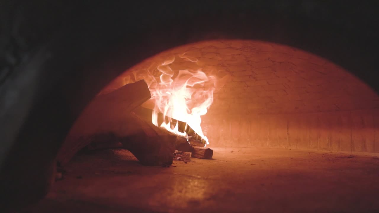 Traditional wood-fired pizza oven with flames, showcasing authentic cooking, rustic ambiance, and artisanal pizza preparation