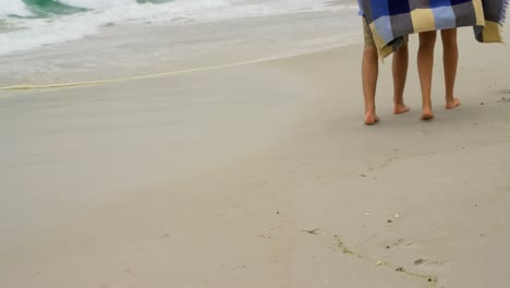 Low-section-of-Caucasian-couple-in-blanket-walking-on-the-beach-4k